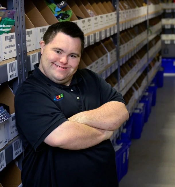John standing with his arms crossed in a warehouse aisle.